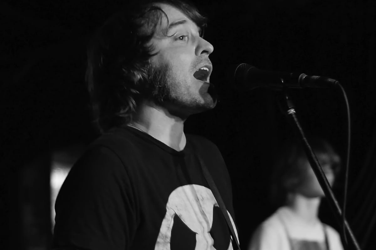 ステージでマイクを前に口を開く人の写真